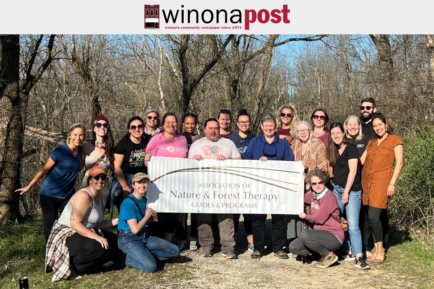 A group gathers outdoors at Eagle Bluff for a photo celebrating their nature-based therapy certificate.